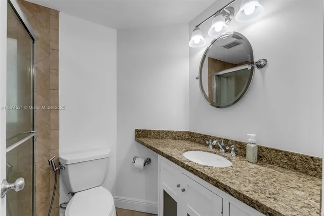 a bathroom with a granite countertop toilet sink and mirror