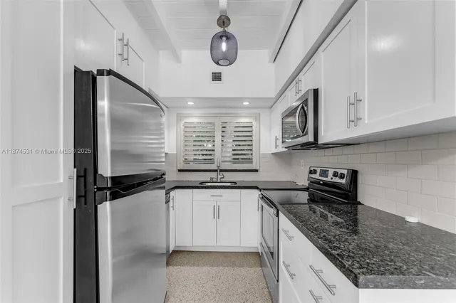 a kitchen with stainless steel appliances granite countertop a sink a stove and cabinets