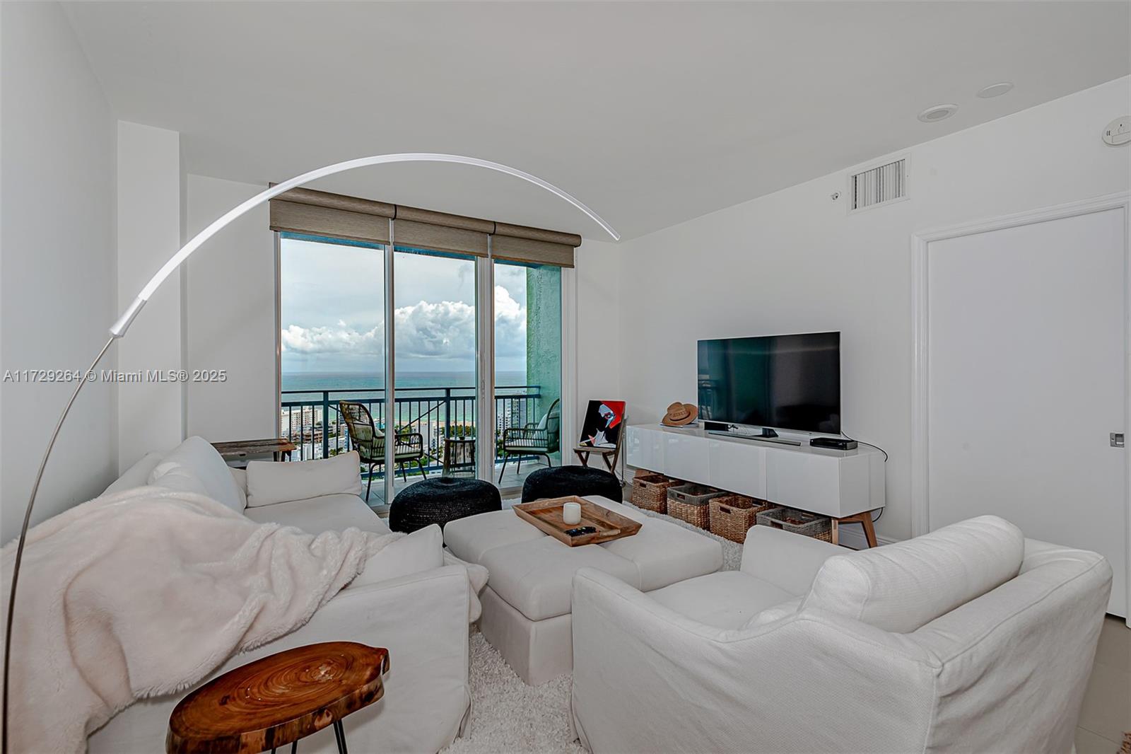 90 Alton Road, Unit PH3205 Miami Beach, FL 33139 - Photo 6 of 28 a living room with furniture a flat screen tv and a floor to ceiling window