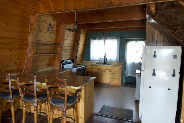 140 East Rim Road Duck Creek Village, UT 84762 - Photo 38 of 45 Kitchen with wood walls, freestanding refrigerator, electric range oven, a kitchen bar, and a peninsula