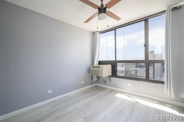 a view of empty room with wooden floor and fan