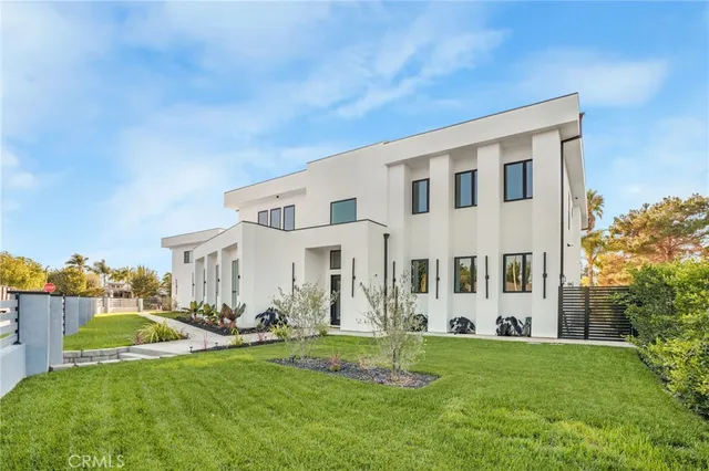 a view of a white house with a big yard potted plants and large tree