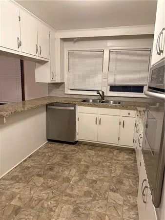 a kitchen with granite countertop a sink a stove top oven and white cabinets