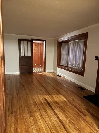 a view of an empty room with wooden floor and window