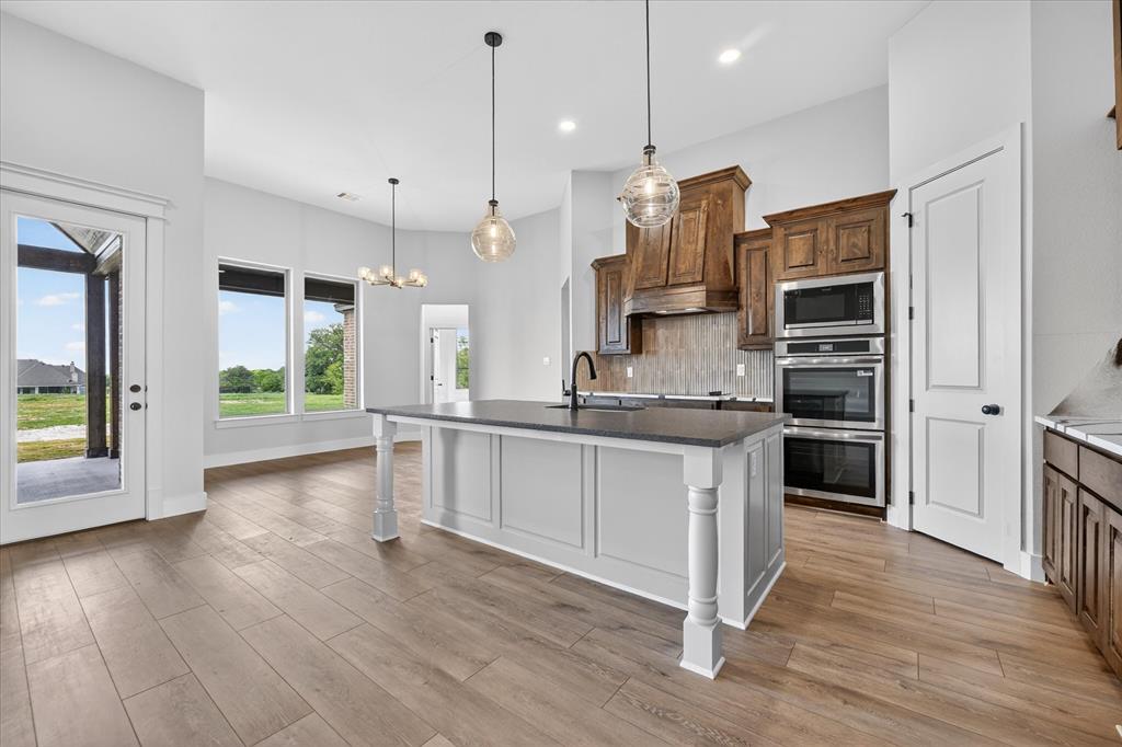 517 Longhorn Lane Springtown, TX 76082 - Photo 14 of 39 Kitchen with an island with sink, stainless steel appliances, a chandelier, and tasteful backsplash