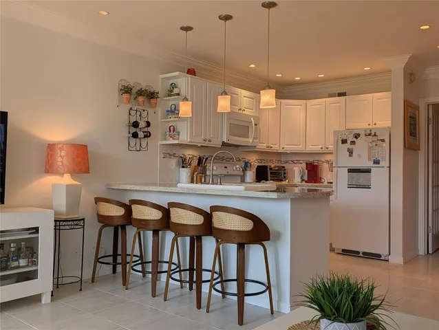 a kitchen with stainless steel appliances granite countertop a table chairs stove and refrigerator