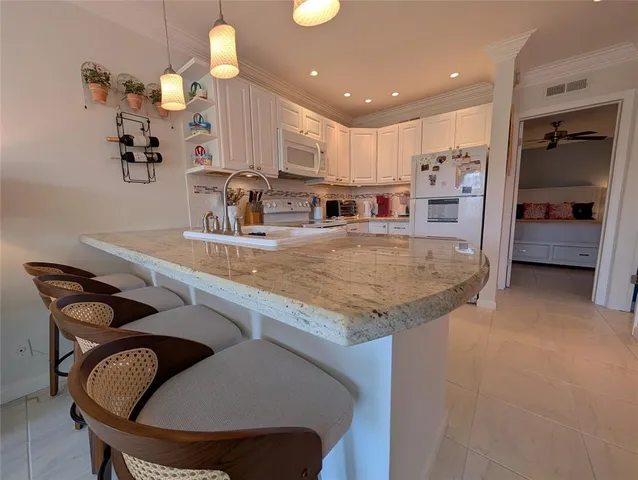 a kitchen with kitchen island granite countertop a table chairs sink and cabinets