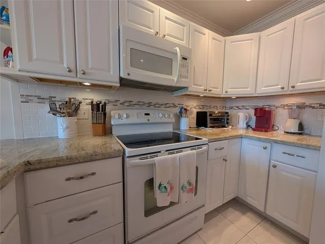 a kitchen with granite countertop white cabinets and white appliances