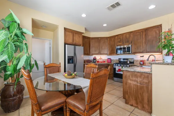 a kitchen with a refrigerator a stove a sink a dining table and chairs