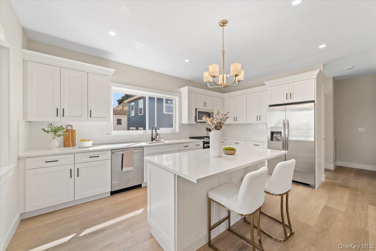 395 5th Avenue New Rochelle, NY 10801 - Photo 8 of 26 a large white kitchen with center island and stainless steel appliances