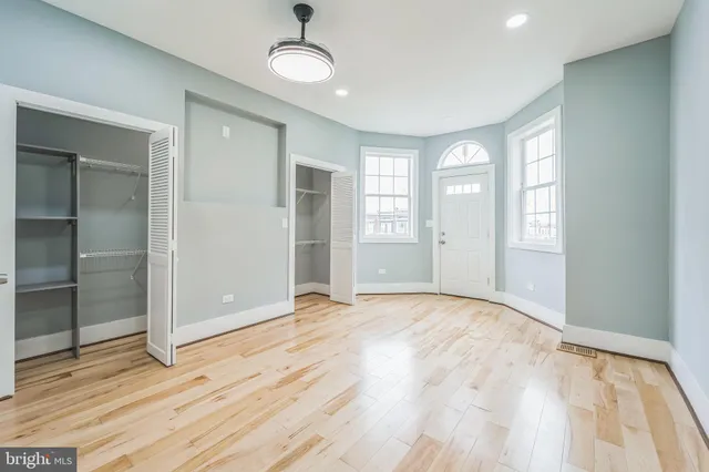 a view of an empty room with window and wooden floor