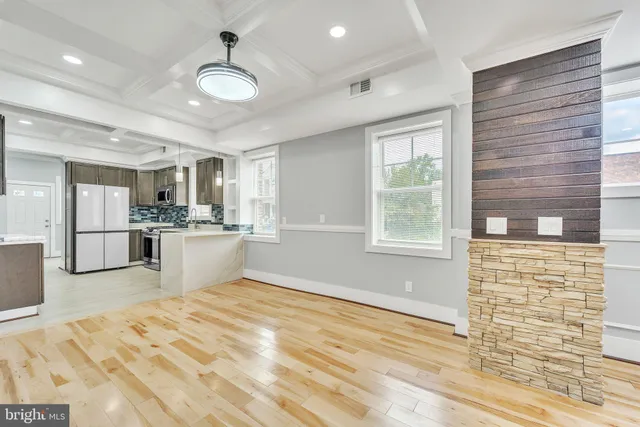 a view of kitchen and empty room with wooden floor
