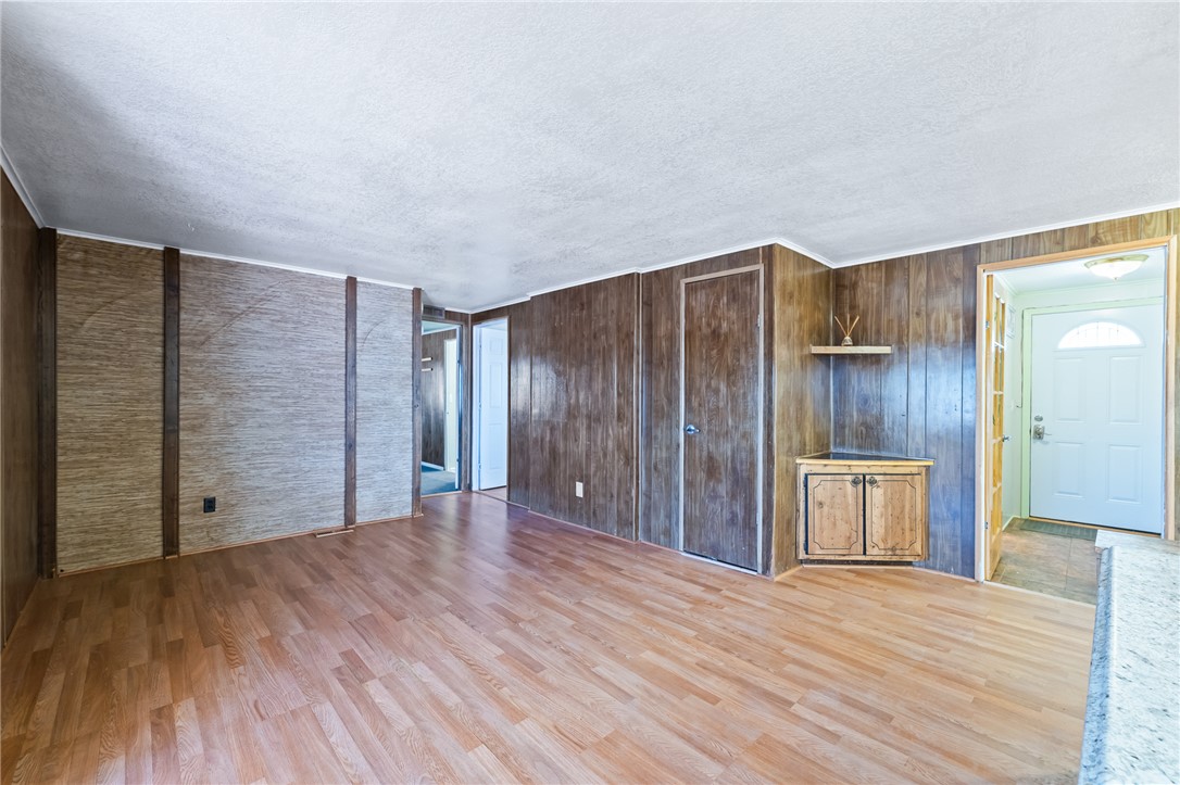3475 Adobe Road Golden Valley, AZ 86413 - Photo 14 of 71 Unfurnished living room featuring light wood-type flooring, a textured ceiling, and wood walls