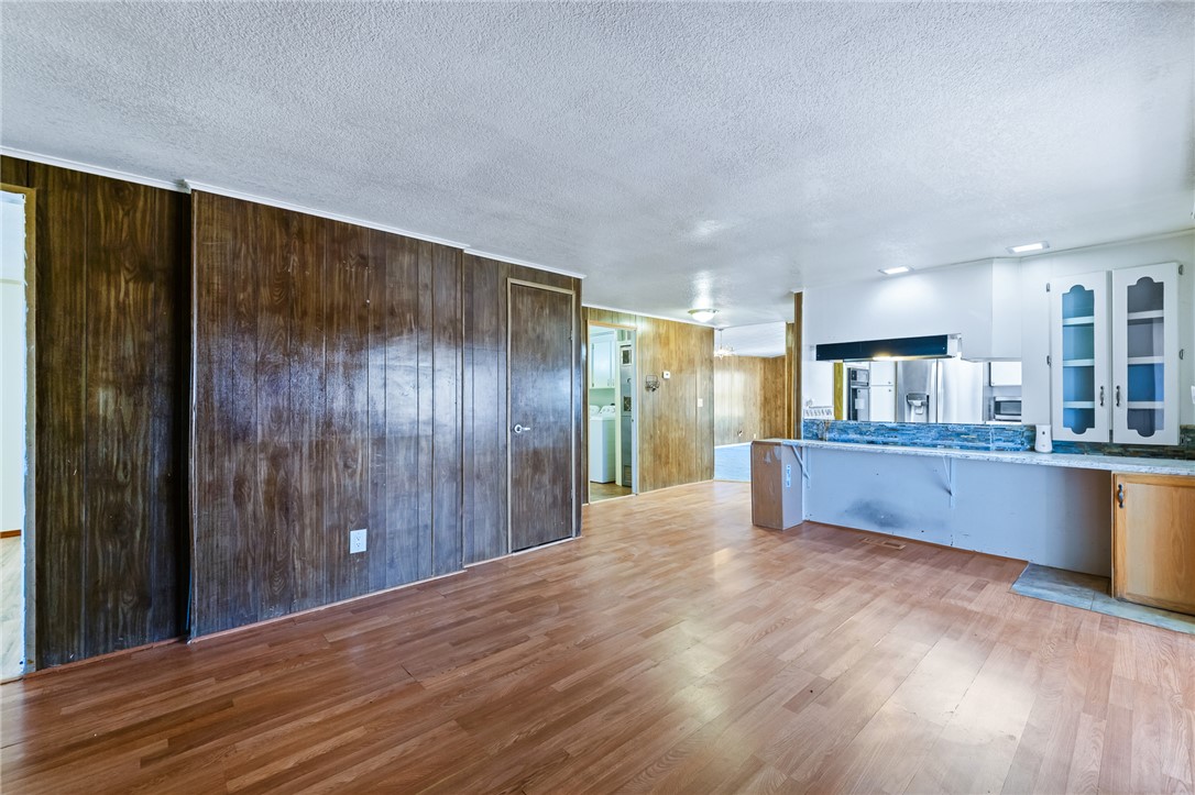 3475 Adobe Road Golden Valley, AZ 86413 - Photo 15 of 71 Unfurnished living room with light wood finished floors, a textured ceiling, and wood walls