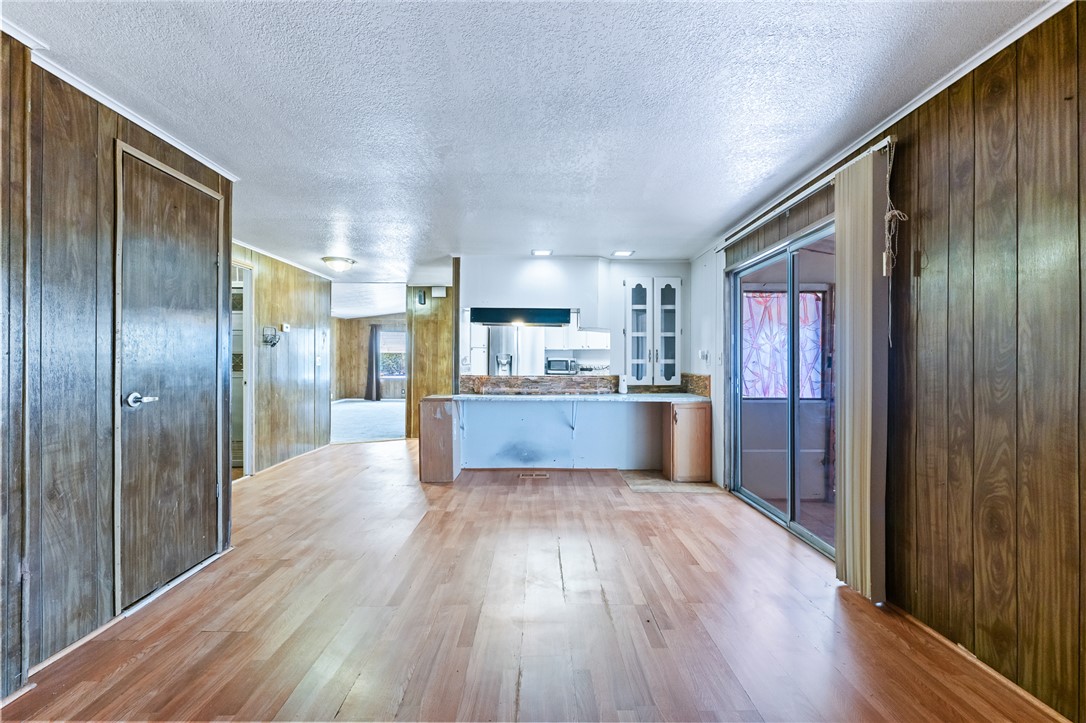 3475 Adobe Road Golden Valley, AZ 86413 - Photo 16 of 71 Kitchen with wooden walls, light wood finished floors, a textured ceiling, white cabinets, and glass insert cabinets