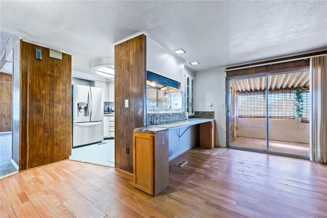 3475 Adobe Road Golden Valley, AZ 86413 - Photo 18 of 71 Kitchen with light wood-style flooring, brown cabinets, stainless steel refrigerator with ice dispenser, a textured ceiling, and wooden walls