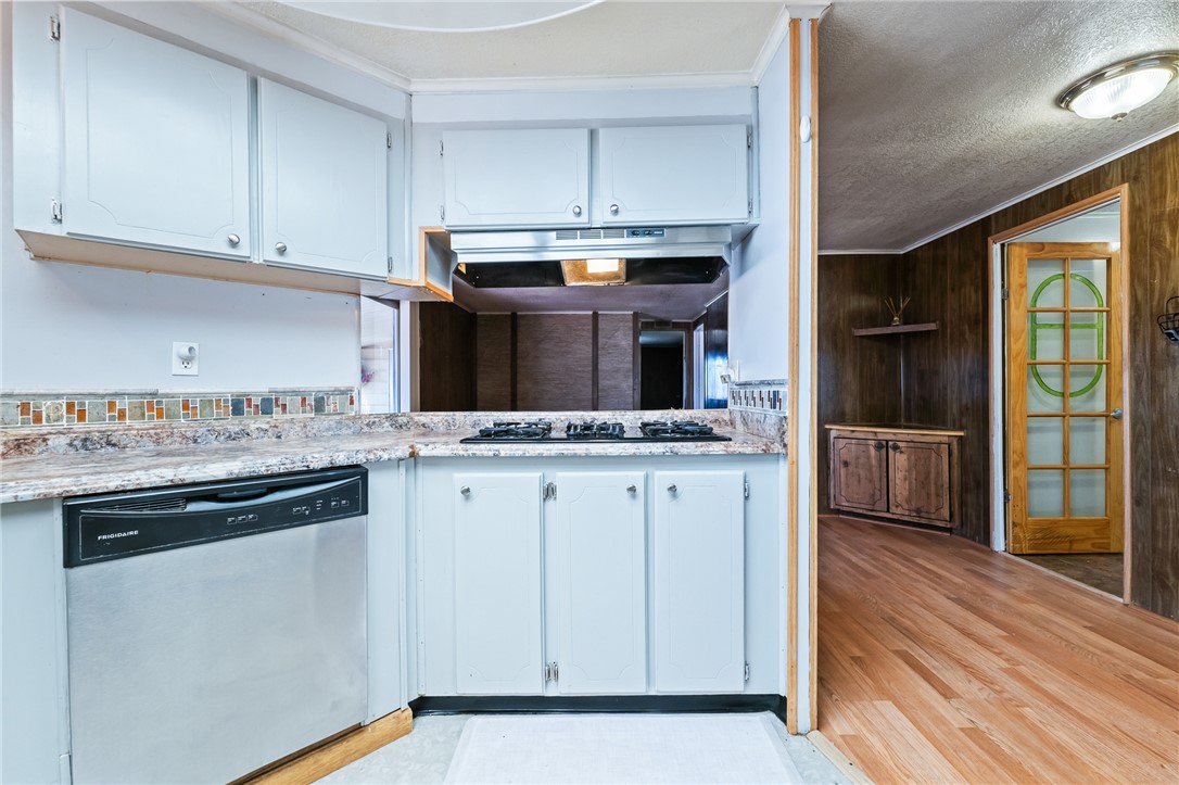 3475 Adobe Road Golden Valley, AZ 86413 - Photo 20 of 71 Kitchen with stainless steel dishwasher, light countertops, wooden walls, a textured ceiling, and white cabinetry