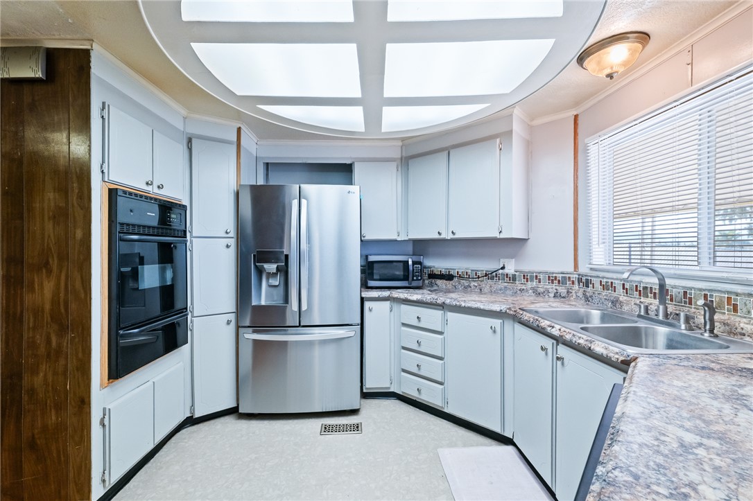 3475 Adobe Road Golden Valley, AZ 86413 - Photo 24 of 71 Kitchen featuring stainless steel appliances, ornamental molding, white cabinetry, a warming drawer, and light countertops