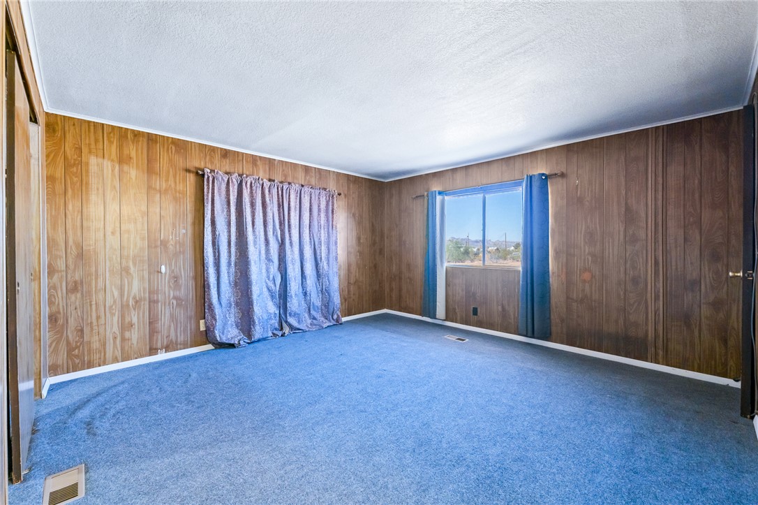 3475 Adobe Road Golden Valley, AZ 86413 - Photo 25 of 71 Unfurnished room featuring carpet flooring, a textured ceiling, and wooden walls