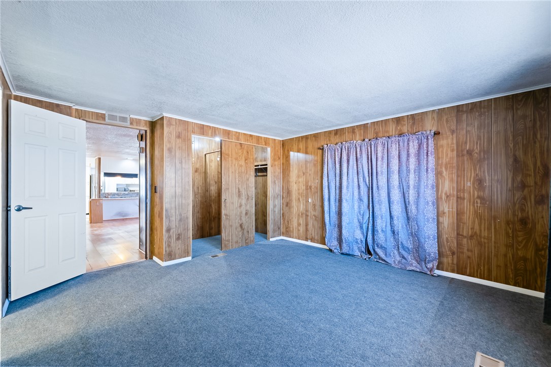 3475 Adobe Road Golden Valley, AZ 86413 - Photo 26 of 71 Unfurnished bedroom featuring carpet floors, wooden walls, a textured ceiling, and a closet