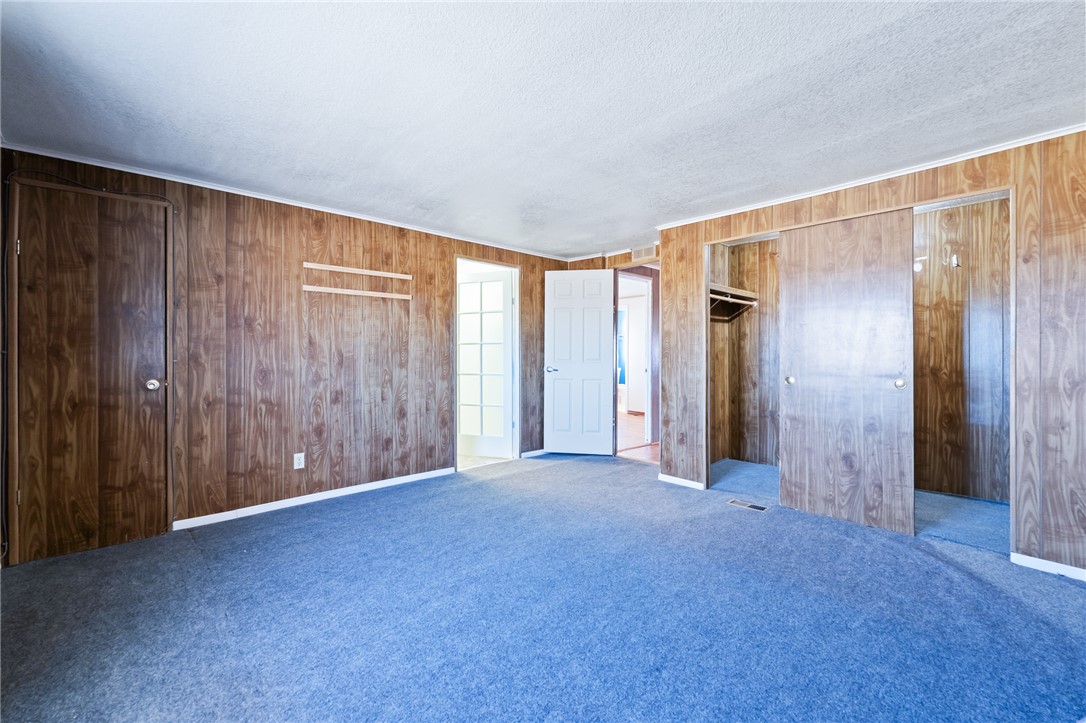 3475 Adobe Road Golden Valley, AZ 86413 - Photo 27 of 71 Unfurnished bedroom with carpet floors, wood walls, a closet, and a textured ceiling