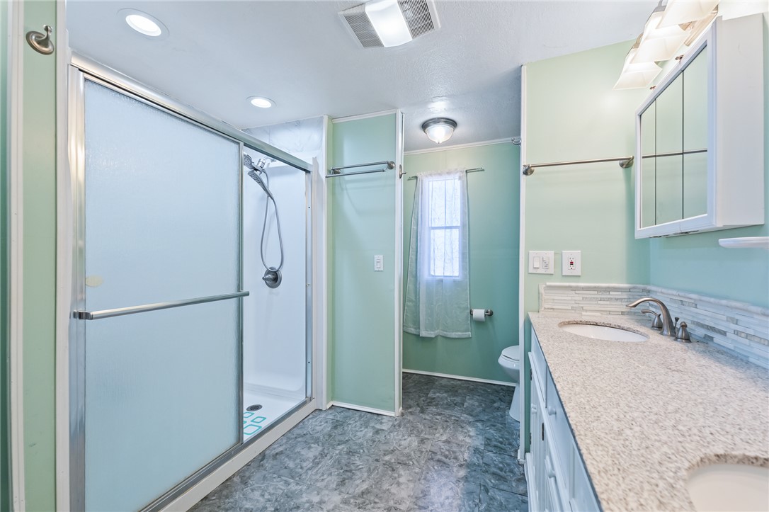 3475 Adobe Road Golden Valley, AZ 86413 - Photo 30 of 71 Bathroom featuring a stall shower, double vanity, crown molding, and decorative backsplash