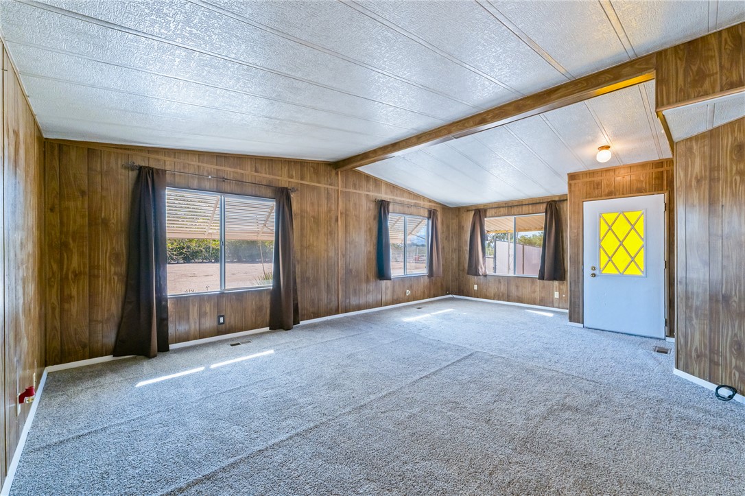 3475 Adobe Road Golden Valley, AZ 86413 - Photo 8 of 71 Unfurnished living room with plenty of natural light, wooden walls, carpet floors, and a textured ceiling