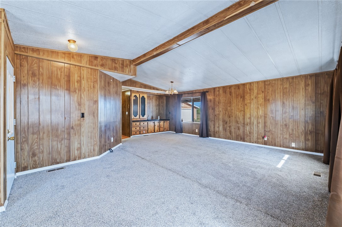3475 Adobe Road Golden Valley, AZ 86413 - Photo 10 of 71 Spare room with carpet flooring, wood walls, and a chandelier