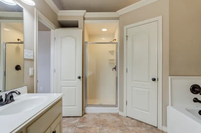 a bathroom with a tub sink vanity granite and shower