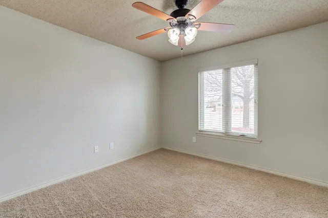 an empty room with a window and a fan