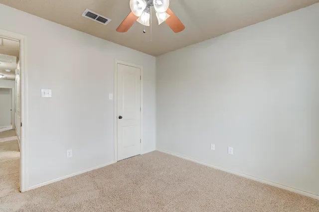 an empty room with a chandelier fan and wooden floor