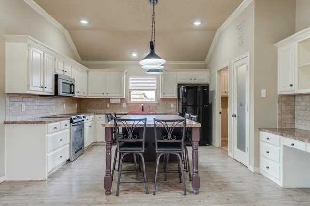 a kitchen with stainless steel appliances kitchen island granite countertop a stove top oven a refrigerator a sink with a dining table and chairs