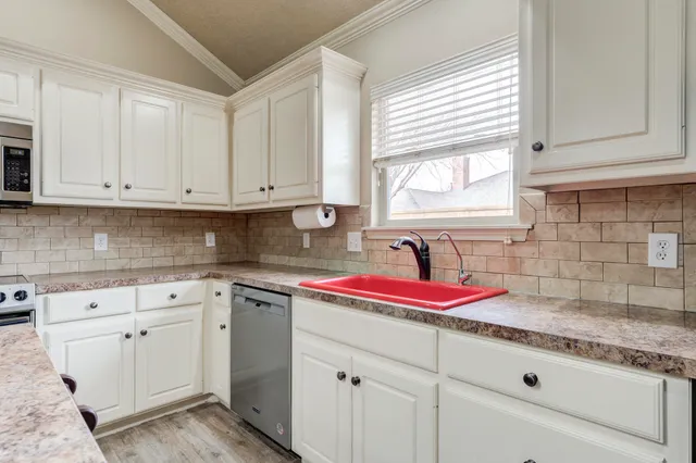 a kitchen with granite countertop cabinets sink and window