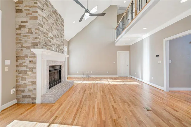 a view of an empty room with wooden floor and a ceiling fan