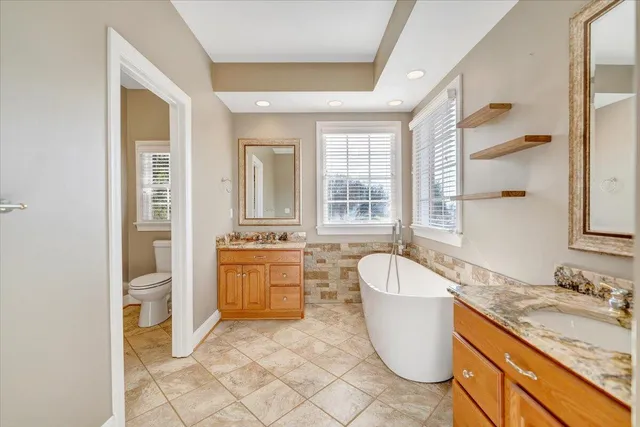a bathroom with a granite countertop sink toilet and mirror