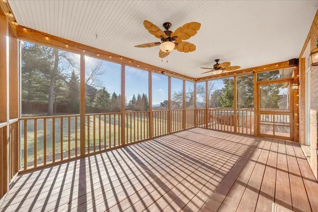 a view of an empty room with chandelier fan and wooden floor
