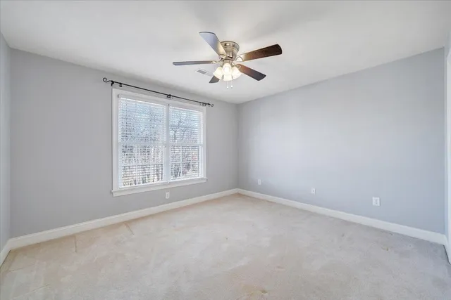 a view of an empty room with wooden floor and a ceiling fan