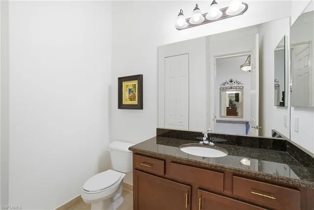 a bathroom with a granite countertop sink a toilet and mirror