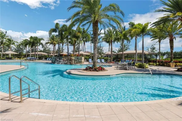 a palm tree sitting in front of a house with swimming pool