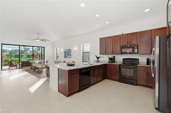 a kitchen with stainless steel appliances granite countertop a stove top oven a sink dishwasher a refrigerator and cabinets with wooden floor