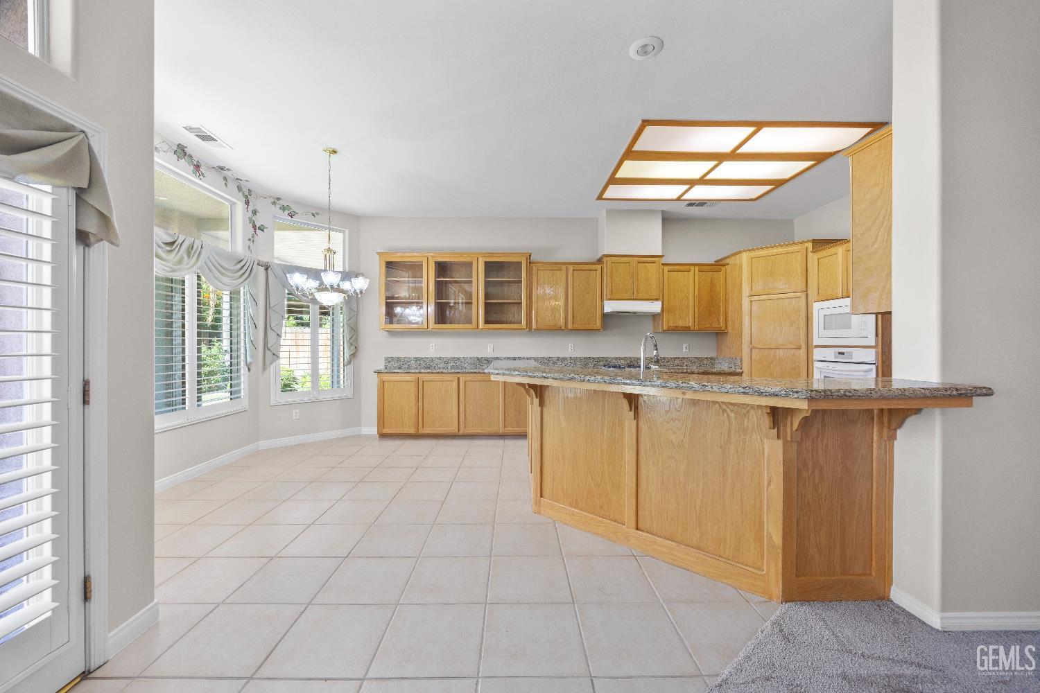 Undisclosed Address Bakersfield, CA 93312 - Photo 18 of 45 a view of a kitchen with kitchen island granite countertop a sink and a view of living room