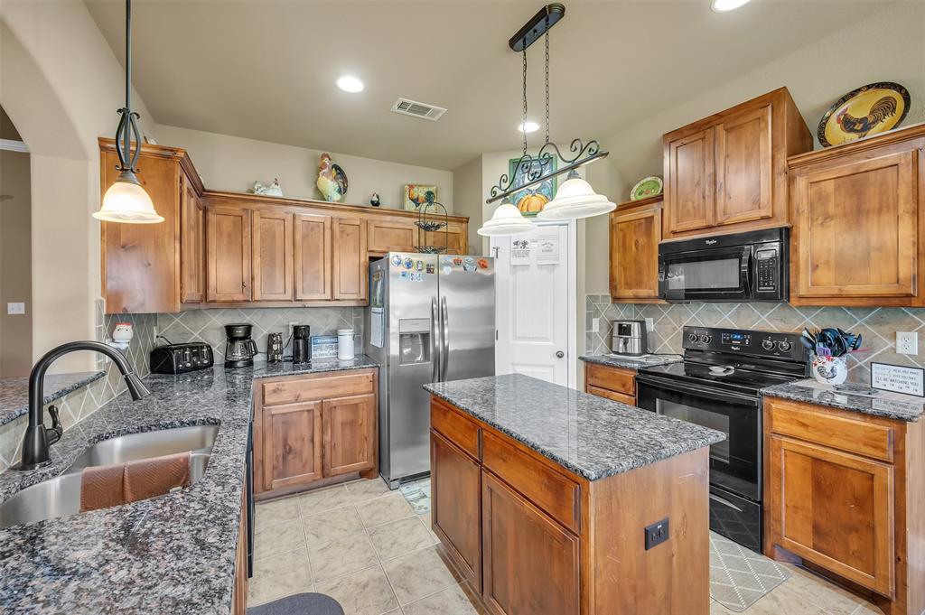 1663 Potomac Drive Burleson, TX 76028 - Photo 8 of 25 a kitchen with stainless steel appliances granite countertop a stove top oven a sink dishwasher and a refrigerator with wooden cabinets