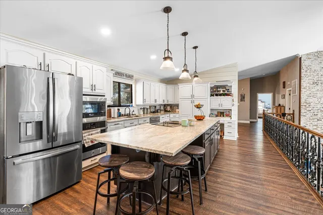 a kitchen with stainless steel appliances a dining table chairs refrigerator and sink