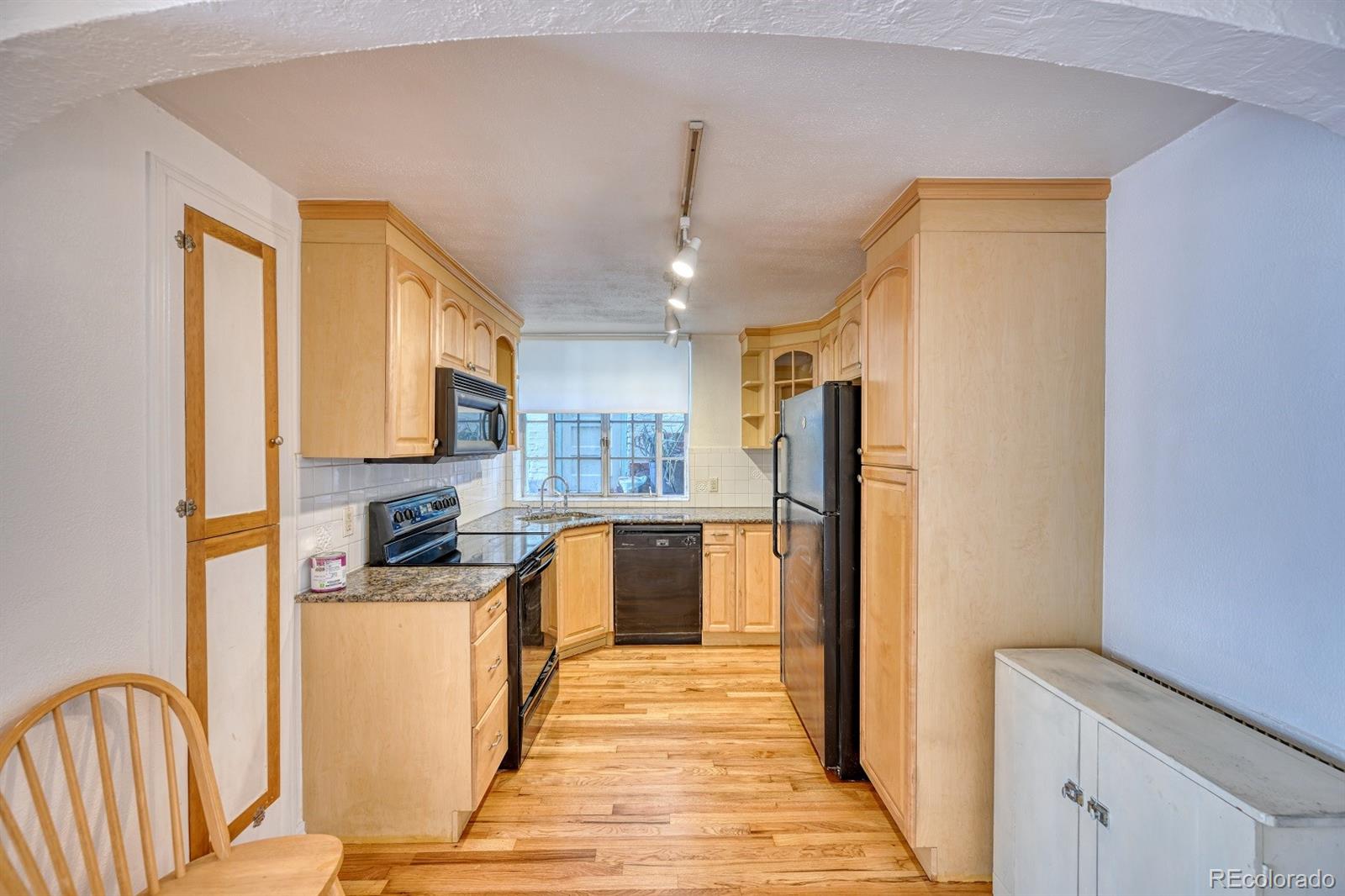 485 South Logan Street, Unit 16 Denver, CO 80209 - Photo 4 of 14 a kitchen with stainless steel appliances granite countertop a refrigerator a stove top oven a sink dishwasher and wooden cabinets
