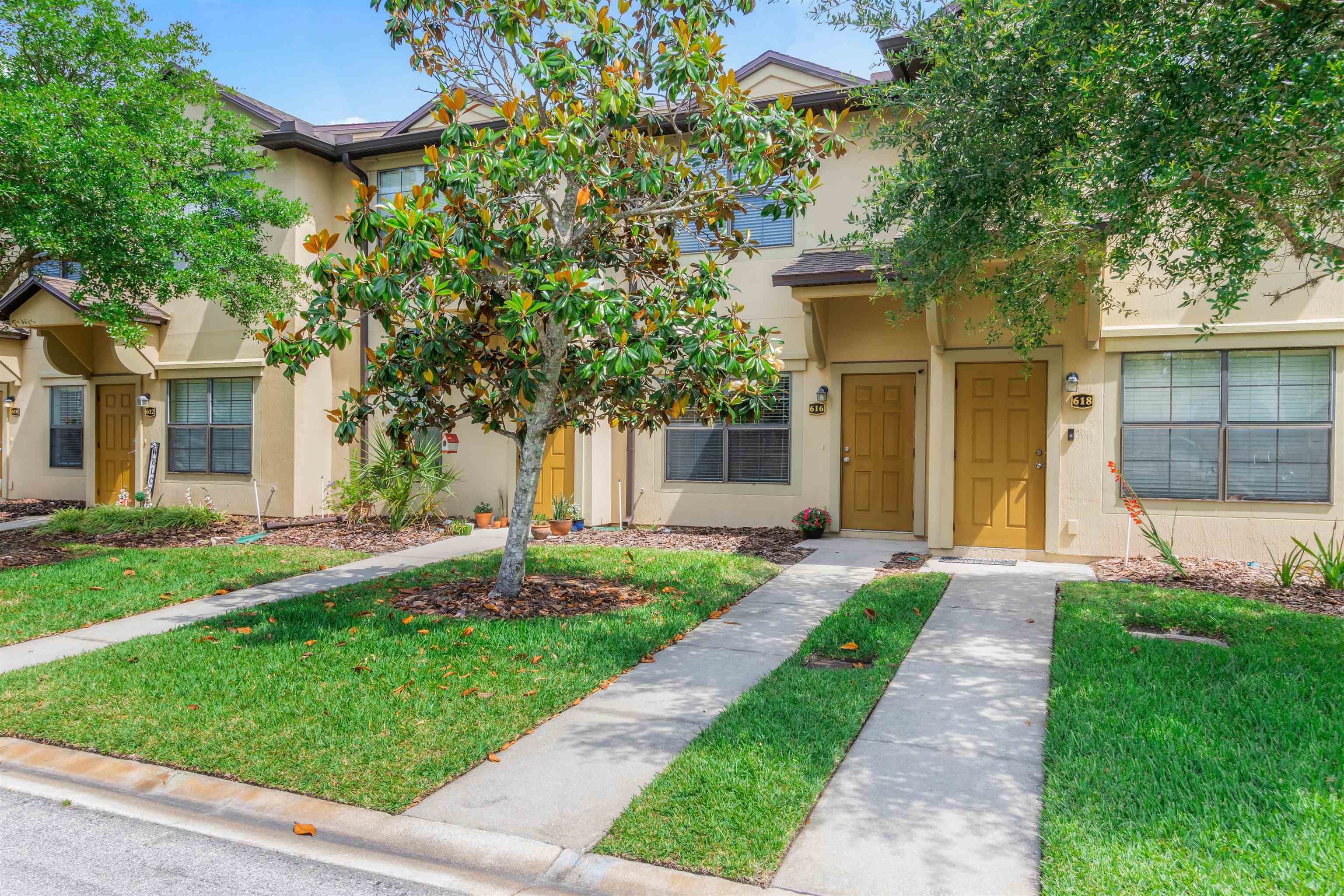 a front view of a house with a yard and a tree