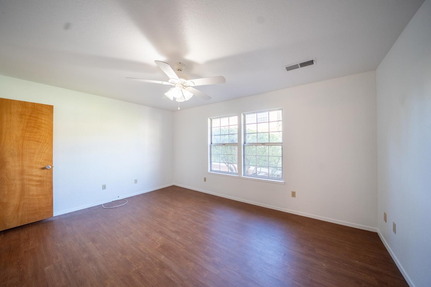 494 Surrey Court Murphys, CA 95247 - Photo 48 of 76 an empty room with wooden floor and windows