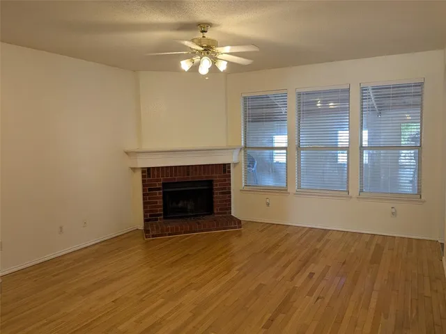 a view of an empty room with wooden floor and a fireplace