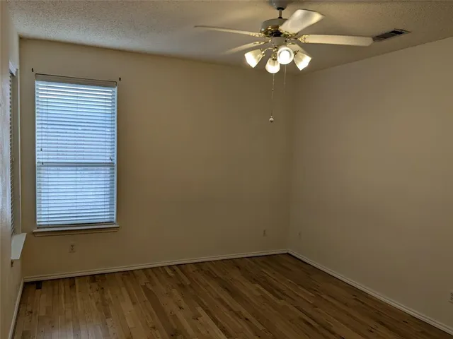 an empty room with a window and a fan
