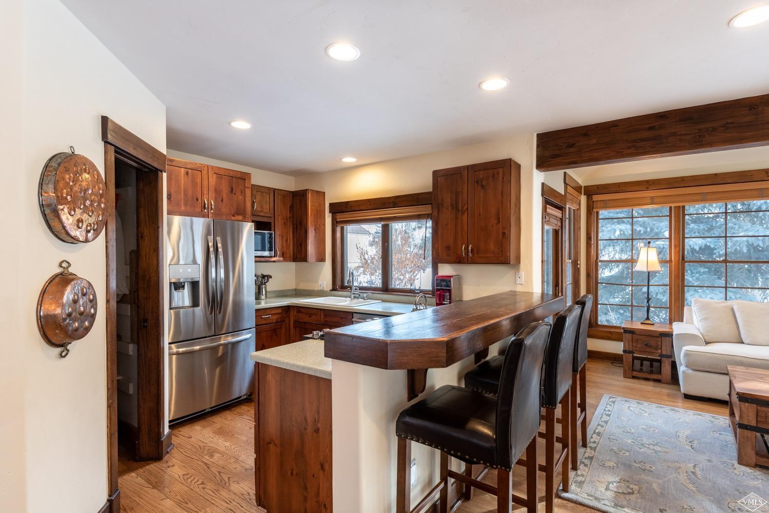 3000 Eaglebend Drive, Unit 13 Avon, CO 81620 - Photo 4 of 25 a kitchen with stainless steel appliances granite countertop a refrigerator a stove a dining table and chairs with a bookshelf