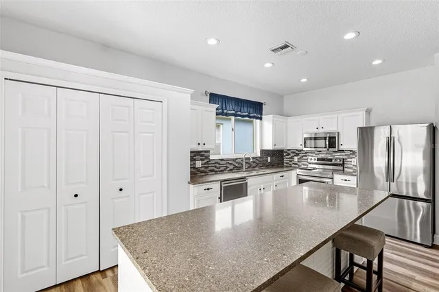 a large kitchen with stainless steel appliances granite countertop a stove a sink and a refrigerator